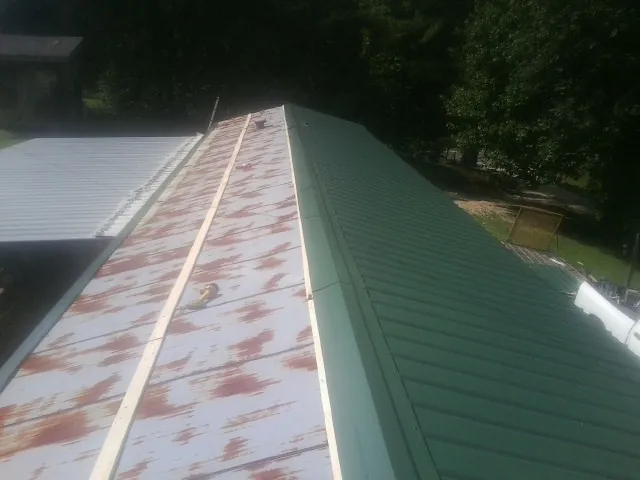 Old rusted panels beside newly installed green metal roofing — Wind Damage Roof Repair by Roofing Brothers in Black Earth