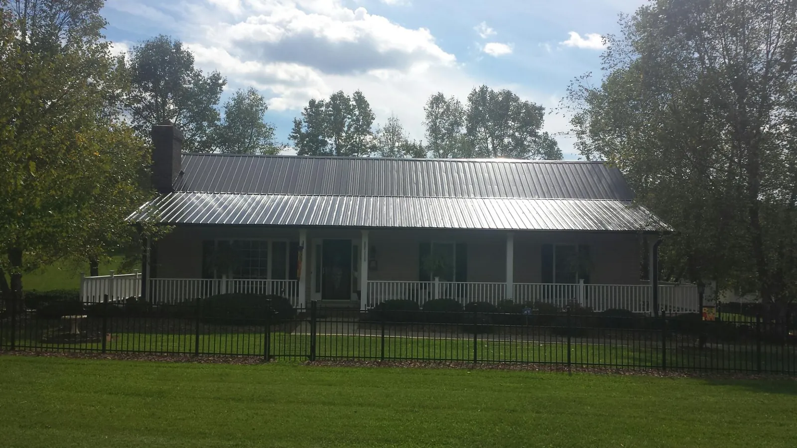 Gray metal roof on a brick ranch with a full width front porch — Gutter Guard Installation work by our crew in Black Earth