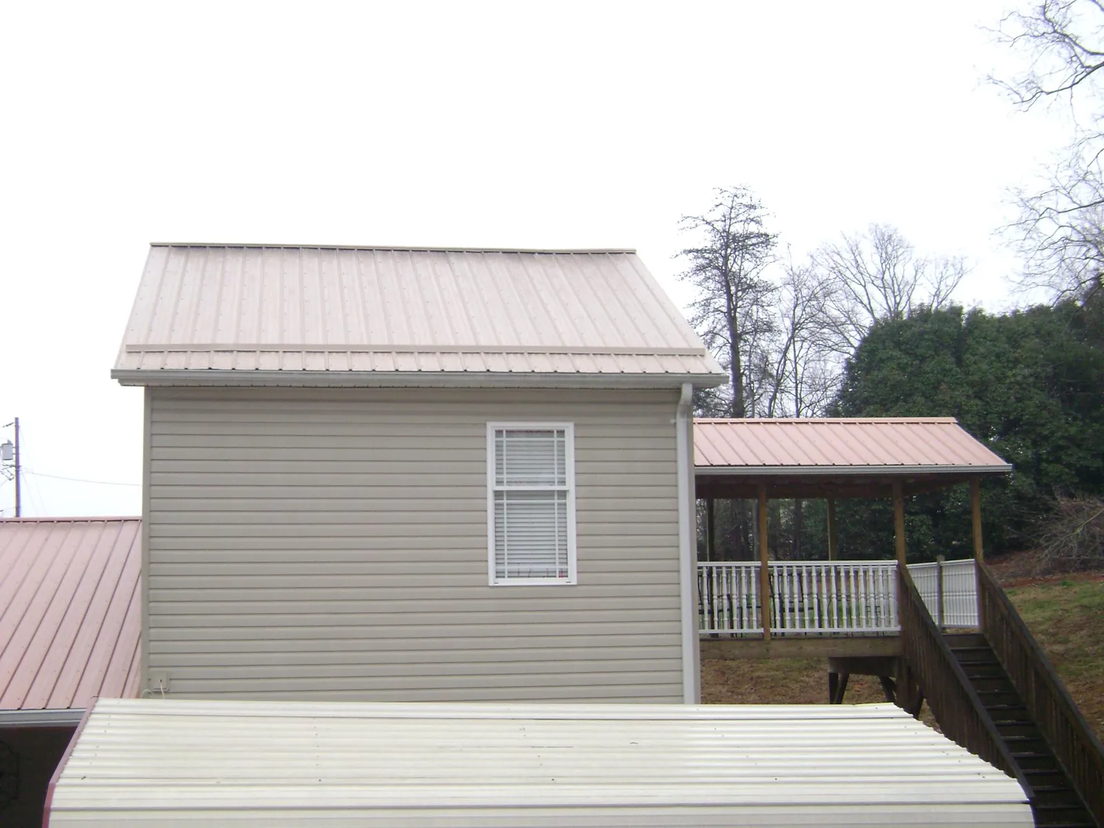 Tan metal roofs on a two story addition and attached porch, from a Roof Replacement job in Black Earth