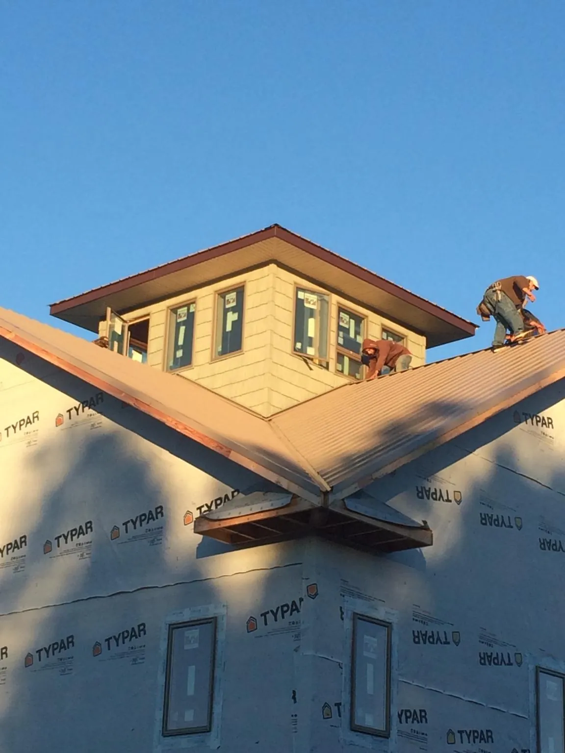 Roofers working around a rooftop cupola on a new metal roof at sunset — Roof Waterproofing in Black Earth by Roofing Brothers